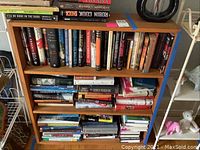 Wood veneer bookcase filled with assorted books showing condition and structure of shelves.