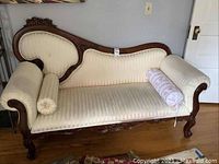 Full front view of Victorian style settee with off-white striped upholstery and carved wood frame