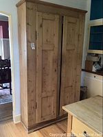 Front full view of armoire showing two paneled doors and base