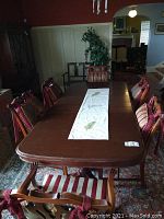 Full view of dining table with chairs showing dark wood finish and scratches.