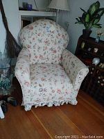 Front view of rocking chair showing floral upholstery and ruffled skirt detail.