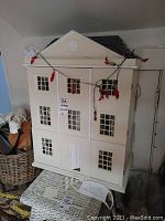 Front exterior view of painted white three-story wooden dollhouse
