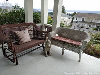Brown and white wicker loveseats on porch with concrete lion statue between them