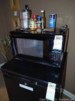 Front view of Emerson microwave with spices and bottle on top, showing keypad and clear door window.