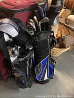 Two sets of golf clubs standing side-by-side in their bags, showing the Maxfli Rev 3 and Acuity logos on bags and clubs, in a storage setting.