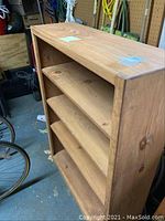 Full view of wooden book shelf showing three shelves and natural wood finish.