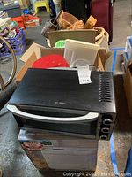 Hamilton Beach black toaster oven on top of Welbilt bread machine box with baskets in background