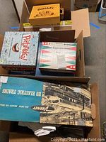 Multiple board games and train set boxes stacked in larger shipping box, visible titles include Gobblet, Backgammon, Pictureka! and Varney train set box.