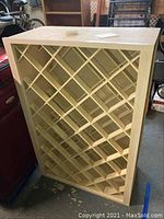 Front view of wooden wine rack with lattice compartments for wine bottle storage.