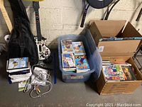 Wide view of two Guitar Hero controllers, game cases in bins and cables on floor