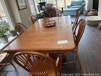 Six oak Windsor chairs around a dining table, showing two armchairs and four side chairs
