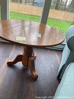 Full view of round oak table with pedestal base near window