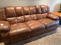 Front view of full three-seat brown leather reclining sofa