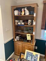 Front view of oak bookcase showing three open shelves and lower double-door cabinet with decorative items in place
