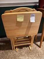 Front view of the wooden TV trays set upright in the stand showing tray tops and stand base.