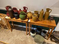 Full view of all pottery pieces on two wooden tables showing variety in shape and color