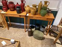Two oak console tables side by side with pottery on top and below
