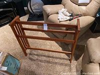 Full view of wooden quilt rack on carpeted floor, showing three horizontal bars for holding quilts.