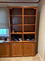 Front view of Amish made wooden bookcase showing upper open shelving with some items stored and lower cabinet closed doors.