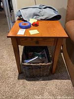 One of the larger oak-finish end tables with simple top and straight legs, basket underneath