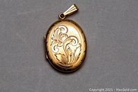 Front of oval locket showing floral scroll engraving and bail