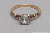 Front view of ring showing round clear stone set in gold prongs