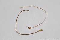 Two gold chain bracelets arranged on gray background, overview view.