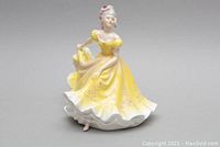 Front view of Royal Doulton Ninette figurine in yellow dress with floral details