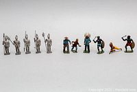 Combined view of six silver-tone soldiers and six painted Native American/tribal warriors, illustrating complete set of approximately 12 toy soldiers.