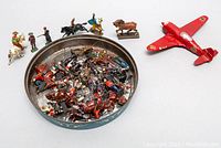 Set of painted English lead toy soldiers, including mounted cavalry and infantry figures, with a red FW 190 German fighter plane model on the side.