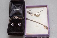 Photo of two sets of sterling silver jewelry including necklaces, matching rings and earrings inside jewelry boxes