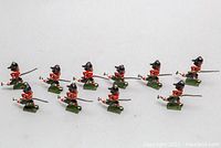 Full view of ten English WWI lead toy soldiers with swords and rifles, showing paint and detail.