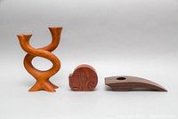 Front view of three wooden items: twisted two-prong candleholder, carved cat puzzle, and sloped wooden candleholder