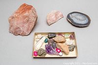 Overview photo showing all crystals and stones arranged in a box with two larger rose quartz and one agate slice outside the box