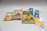 Full view of the children's books and Barbie fashion booklets spread on a gray surface