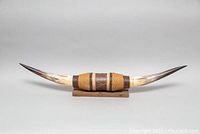 Overall side view of the mounted cow horn showing leather accents and wooden base, decorative item.