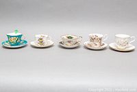 Full frontal view of the five teacups and saucers showing variety of floral patterns and brands.