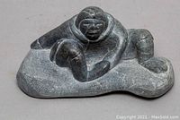 Oblique front view showing figure lying on base