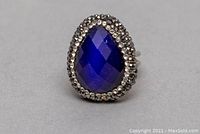 Front view of ring showing large blue faceted teardrop-shaped crystal surrounded by small silver-tone crystals.