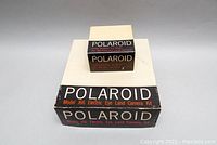 Two boxes including the Polaroid J66 Electric Eye Land Camera kit box and the smaller Polaroid Color Adapter Kit 660 box stacked together on a plain background.