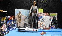 Overview of Star Wars collectibles assortment including figures, books, vinyl album, and lightsaber with vintage small vehicle toy