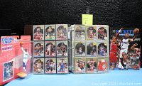 Padded brown binder open to several pages of sleeved NBA basketball trading cards, New/Sealed Vin Baker Starting Line-Up figurine in packaging, and Beckett Basketball Monthly #55 magazine