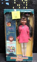 Front view of Jessi Ramsey doll in original blue-striped box, showing doll in pink dress, white tights, pink shoes, and gold earrings.
