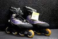 Side view of the pair of K2 inline roller blades with purple soft boot, black frame, yellow wheels, showing the left and right skate side by side.