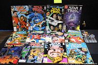 Front view of all Star Trek comic books displayed in two rows with covers visible, including titles and characters, along with the figurine and pins arranged at the top right.