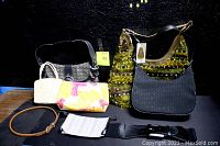Lot of 8 women's accessories including purses, cosmetic bags, and belts. Items arranged on a wooden surface with dark background. Visible tags on one purse.