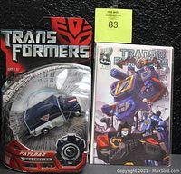 Full view of Transformers Payload Decepticon armored truck figure still in packaging beside bagged comic book.