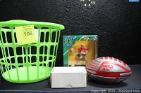 Photo showing fluorescent lime green laundry basket, sealed Joe Montana figurine box, white box likely containing trading cards, and red/gray Hedstrom G2 Air foam football
