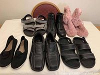 Full view of assorted shoes on table includes men's dress shoes, sandals, women's ballet flats and fuzzy slippers