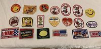 All patches laid out on white surface showing variety including smiley face, cartoon characters, and racing logos.